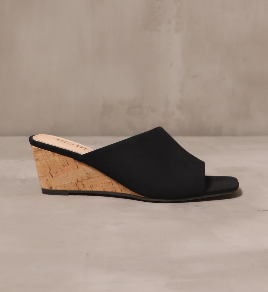 outer side of the black wedge of darkness heel with black tread, upper, and toe bed